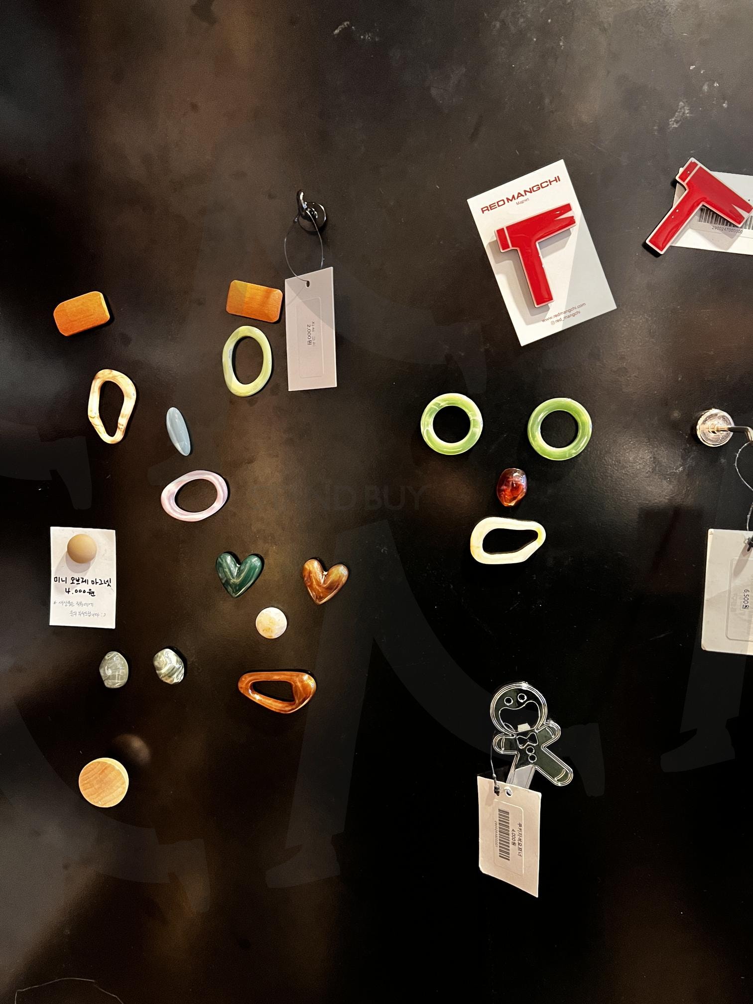 검은색 벽에 붙어 있는 여러 가지 모양의 물건들 | 자석, 장식, 벽면, 고리, 하트, 사람 모양, 액세서리, 가격표, 부착물 | 스탠바이 STANDBUY 디지털 콘텐츠