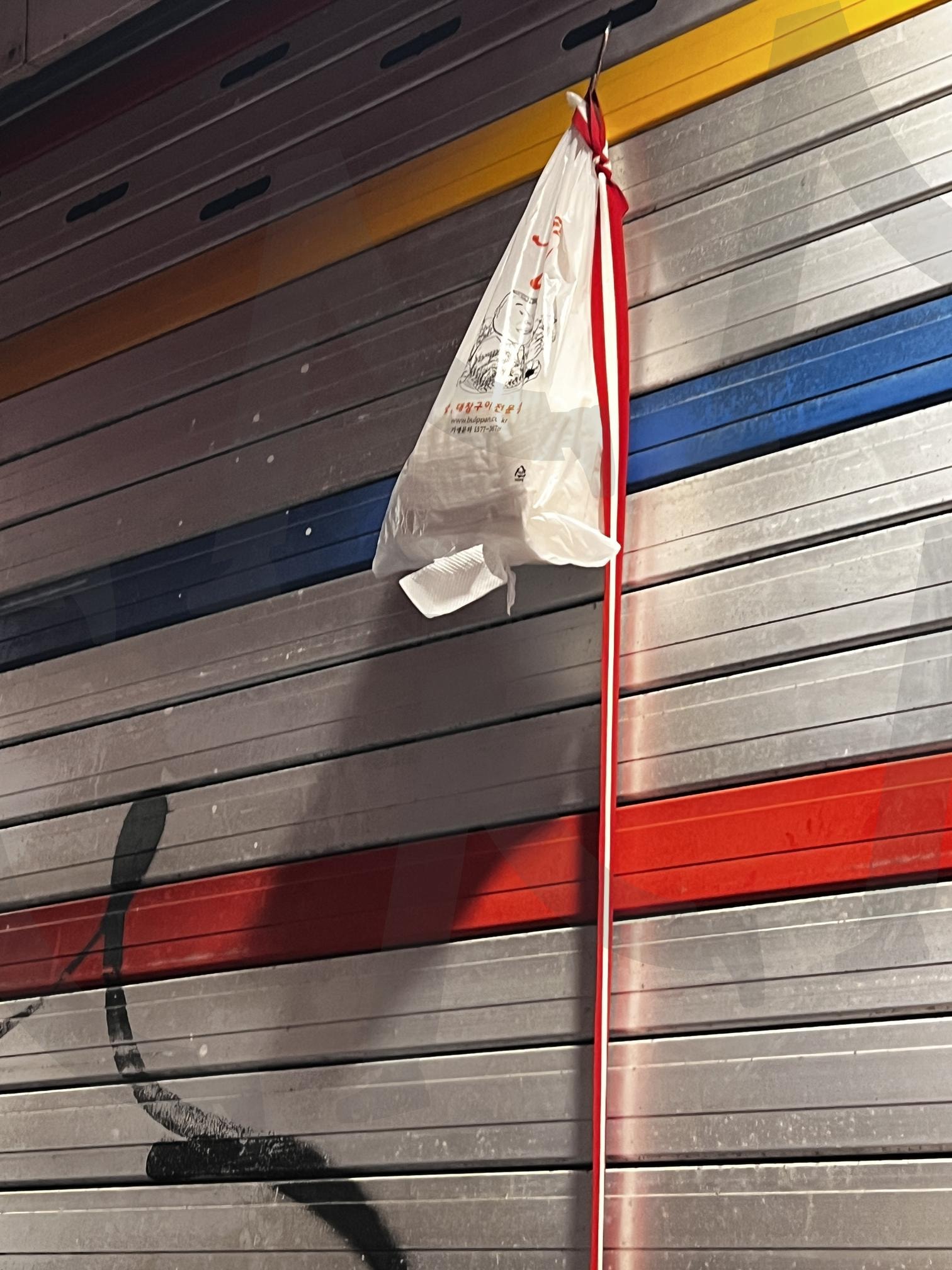 붉은색 리본이 묶인 비닐 봉투 | 비닐 봉투, 봉투, 붉은색 리본, 리본, 걸이, 금속 걸이, 벽, 회색 벽, 그림자 | 스탠바이 STANDBUY 디지털 콘텐츠